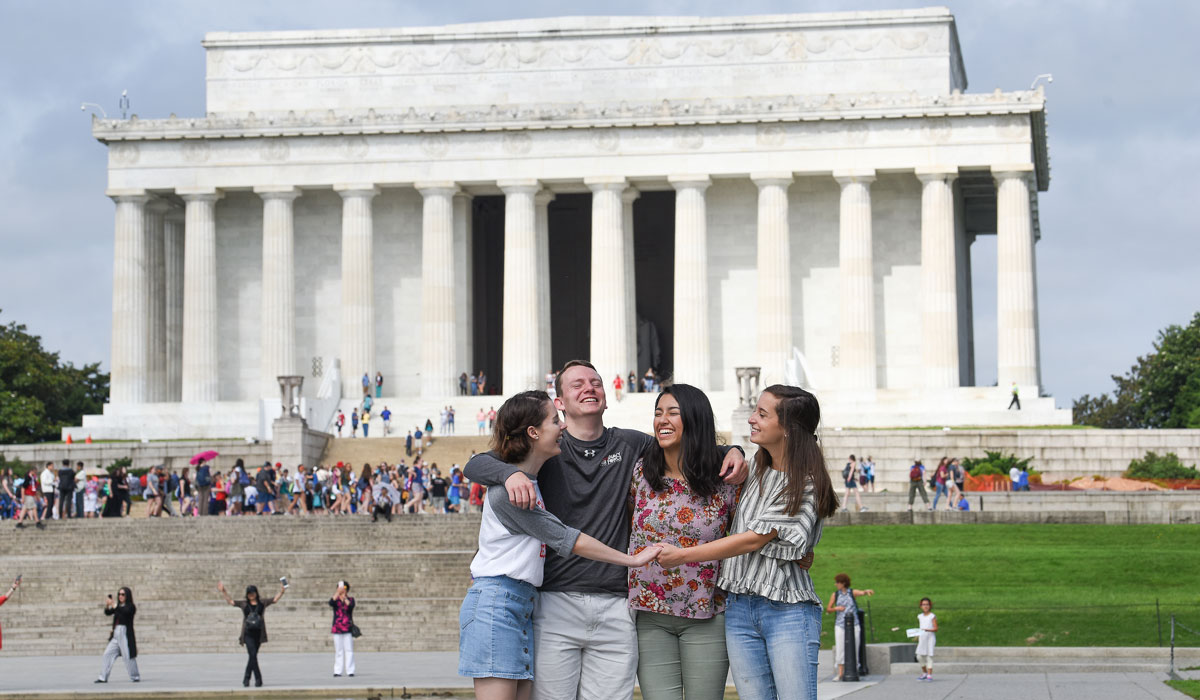 Catholic University students hugging in front of the Lincoln Memorial 